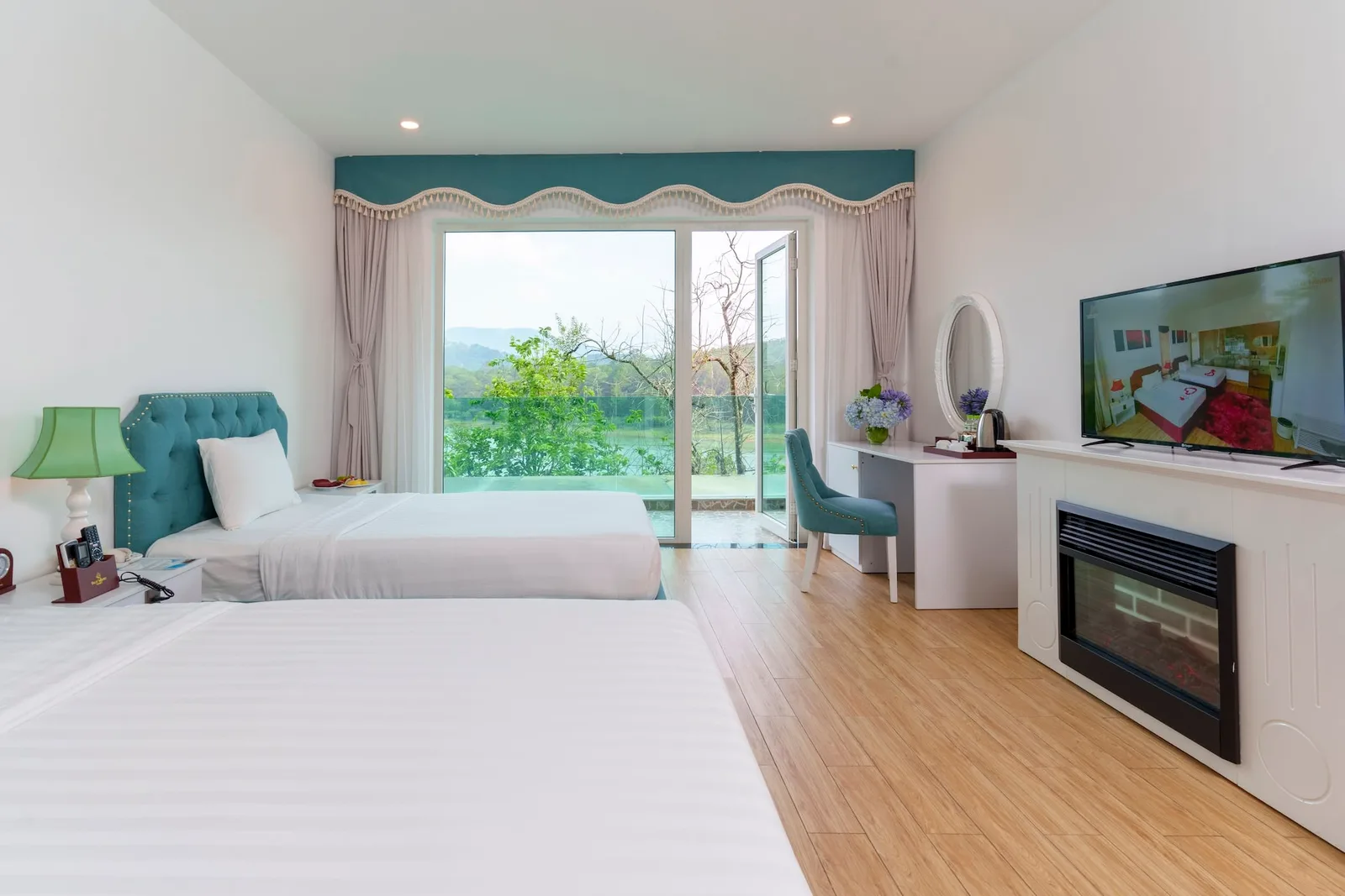 Phòng Family Lake View của Dalat Wonder Resort với hai giường đôi, lò sưởi điện và cửa kính mở ra mặt hồ