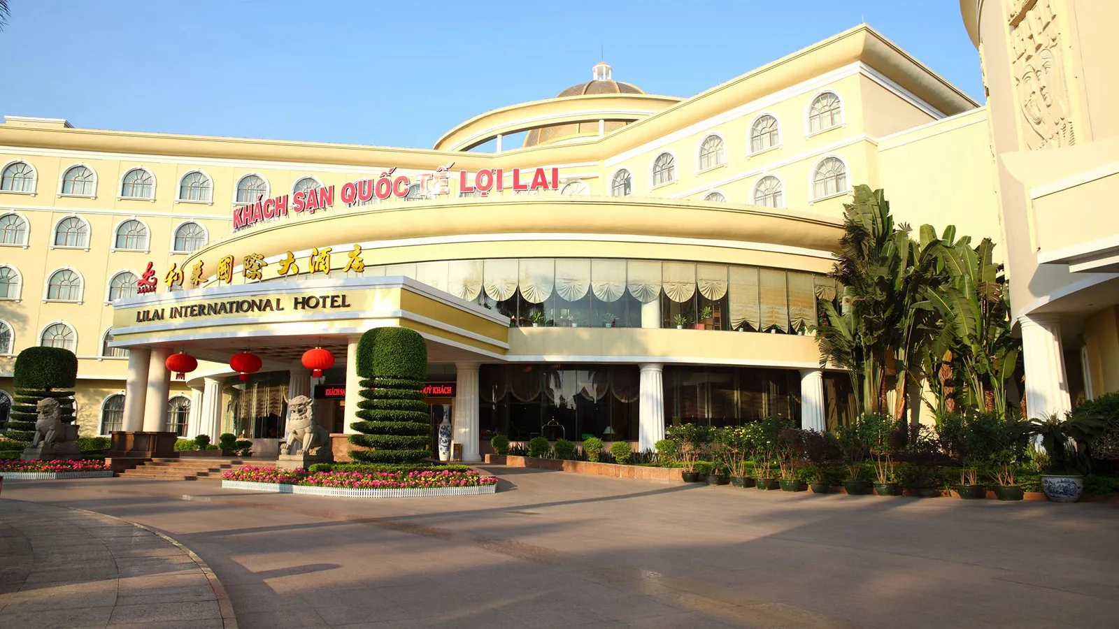 Sảnh chính Khách sạn Quốc tế Lợi Lai với mái vòm cong màu kem, biển tên tiếng Việt, tiếng Trung và tiếng Anh, đèn lồng đỏ và tượng sư tử đá