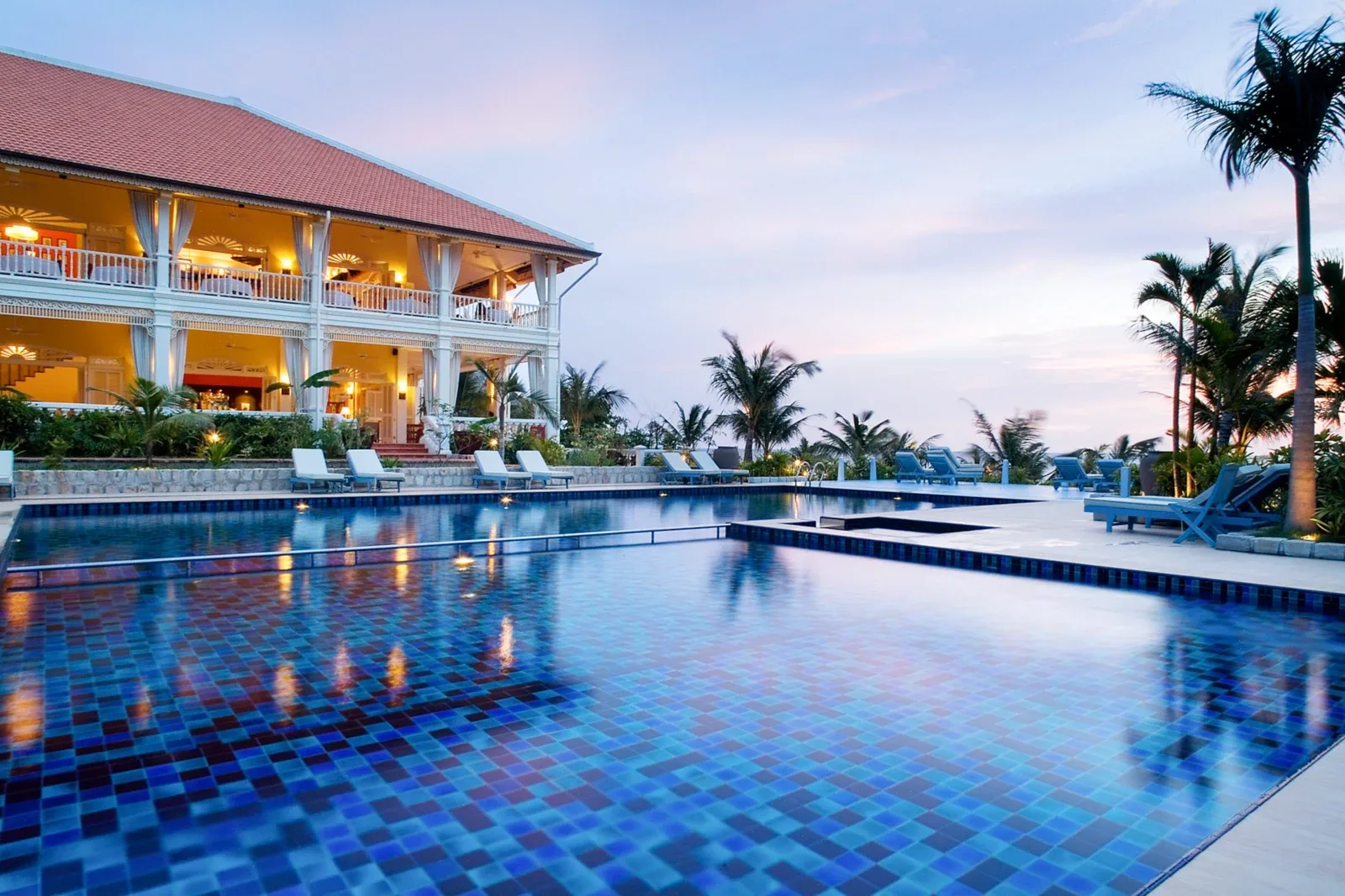 Nhà chính La Veranda Resort Phu Quoc kiến trúc thuộc địa Pháp mái ngói đỏ bên hồ bơi lúc chiều tối
