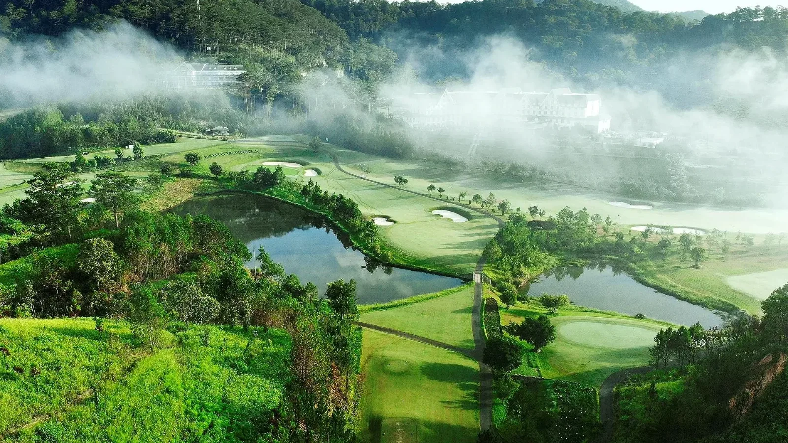 Sân golf SAM Tuyền Lâm cạnh Swiss-Belresort Tuyen Lam Dalat nhìn từ trên cao, hồ nước xen giữa các đường fairway và sương phủ đồi thông