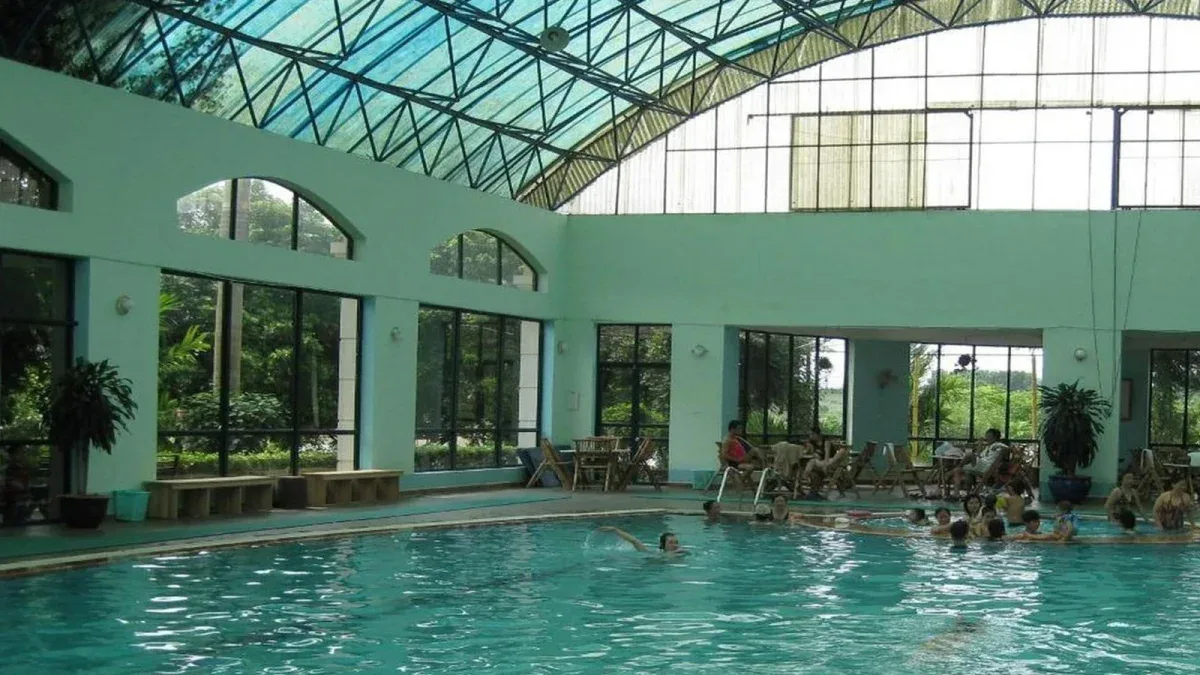 Bể khoáng nóng trong nhà mái vòm kính tại Tản Đà Spa Resort, khách đang ngâm và bơi