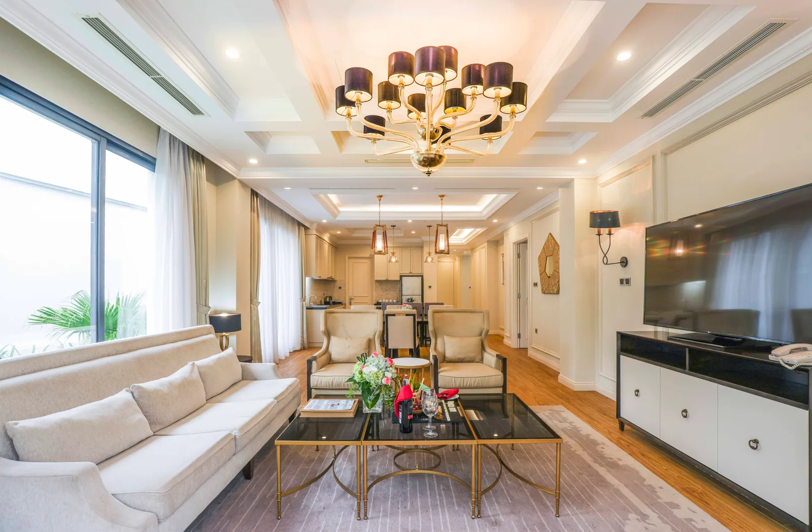 Phòng khách villa Vinpearl Resort & Spa Đà Nẵng với đèn chùm, sofa kem và bếp phía sau